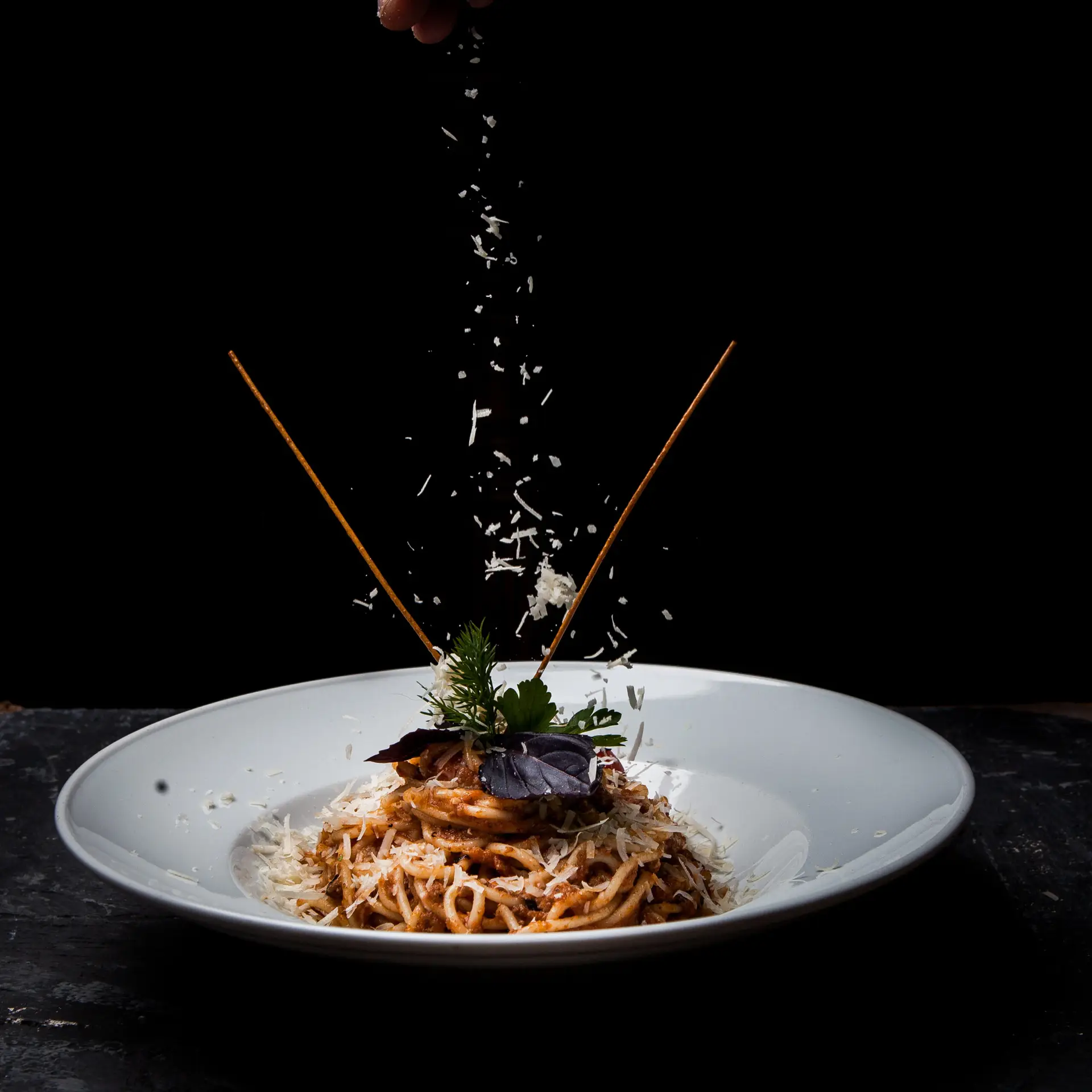 side view spaghetti with greens and ricotta cheese in round white plate on stone background